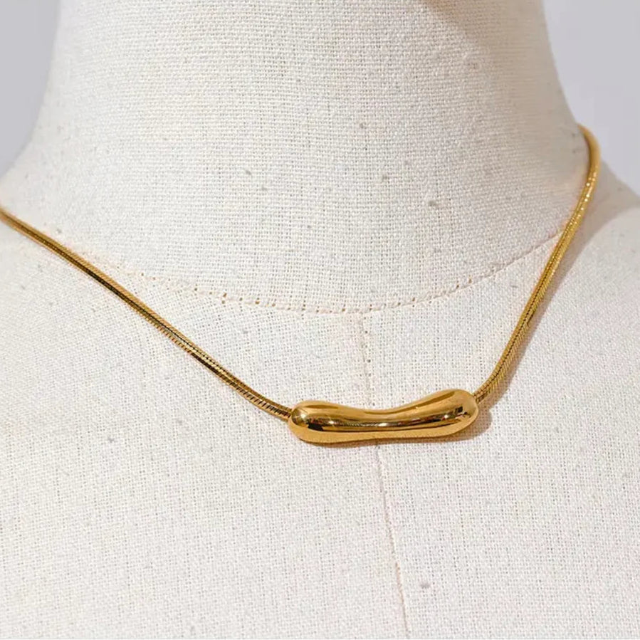 Gold necklace on a mannequin bust against a white background