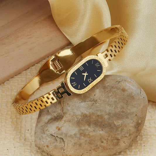 Gold bracelet with a black dial on a stone surface