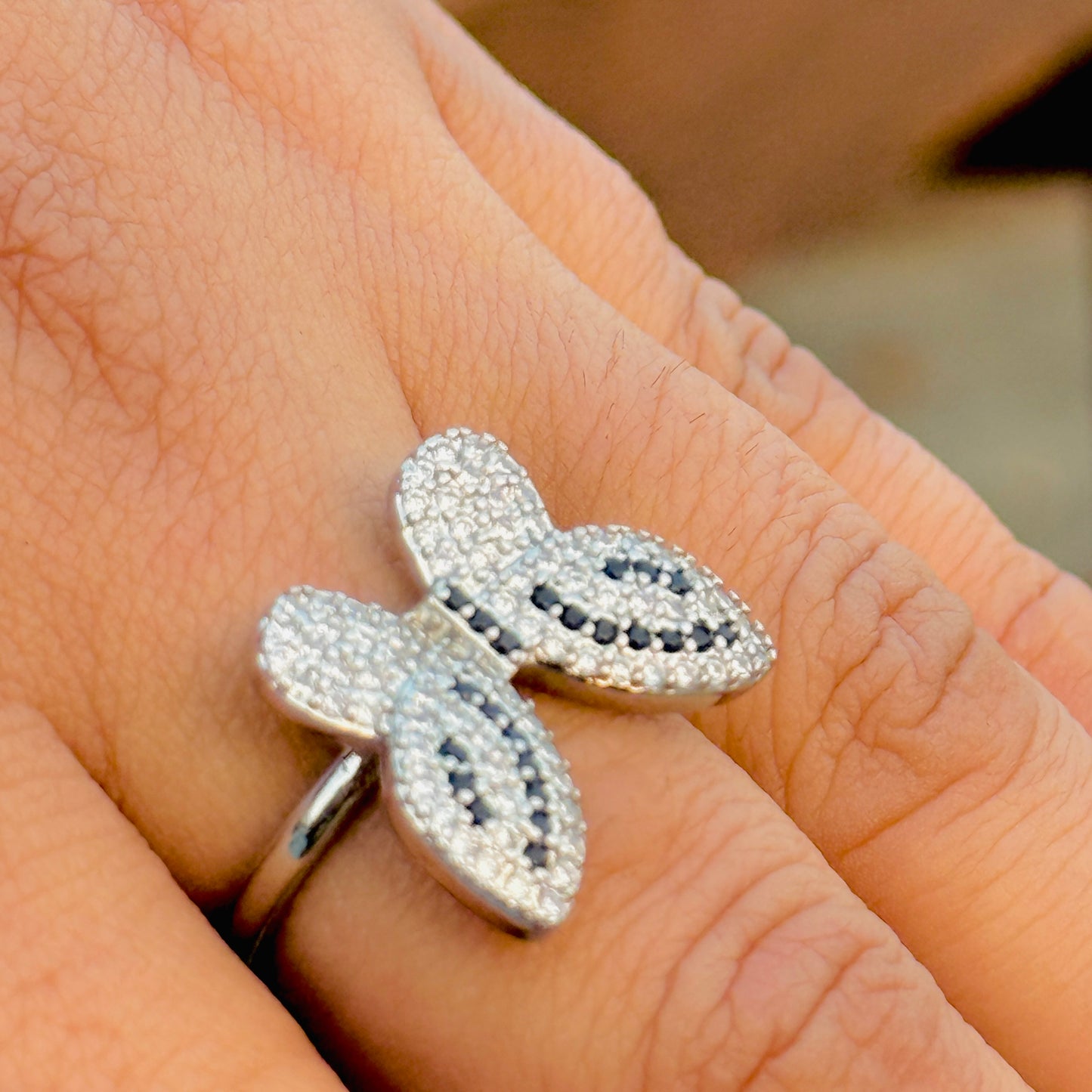 Silver butterfly-shaped ring with gemstones on a finger
