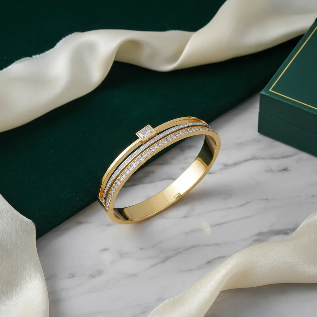 Gold ring with diamonds on a marble surface with green fabric and white ribbons.