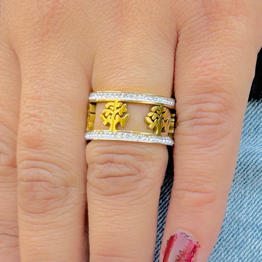 Gold and silver ring with tree design on a finger