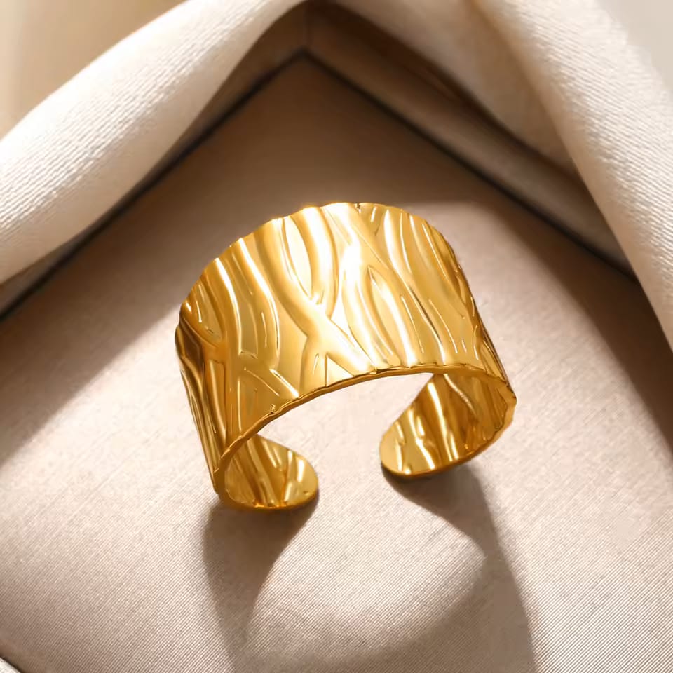 Gold cuff bracelet on a beige fabric background