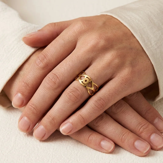 Close-up of a hand wearing a gold ring on a light background