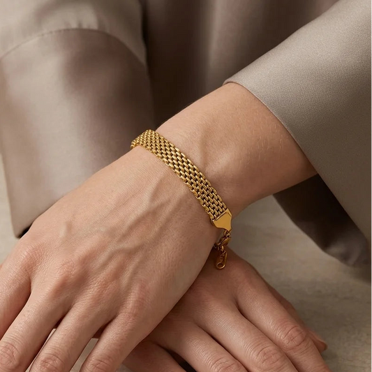 Gold bracelet on a person's wrist with a neutral background