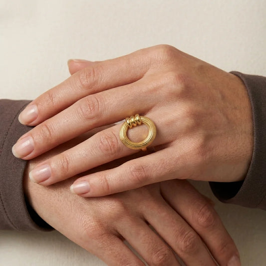 Gold ring on a hand against a neutral background