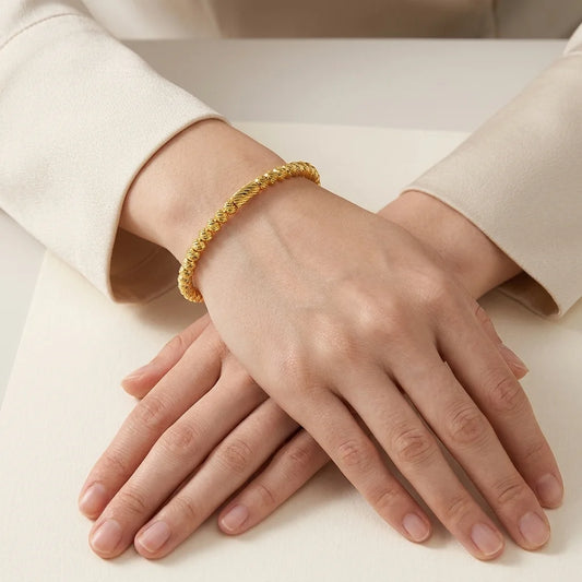 Gold bracelet on a person's wrist with a neutral background