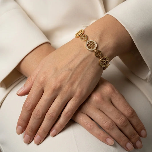 Gold bracelet on a person's wrist with a neutral background