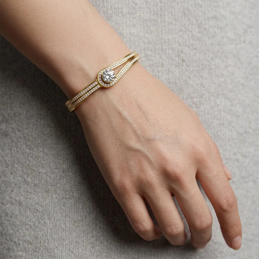 Gold bracelet with a diamond on a wrist against a neutral background