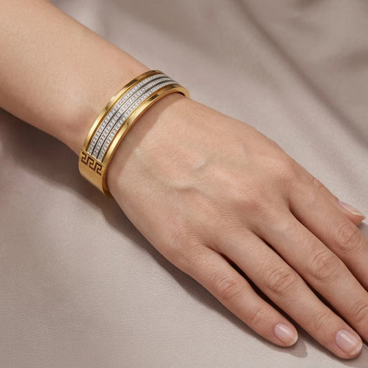 Gold bracelet on a wrist against a neutral background