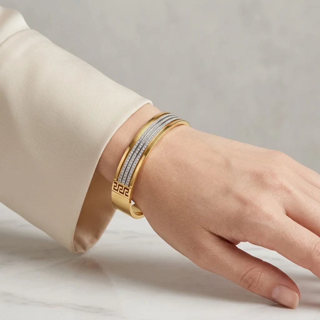 Gold bracelet on a person's wrist against a neutral background