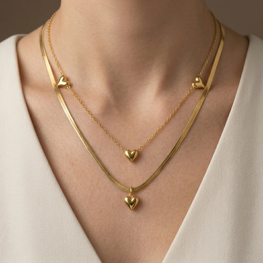 Gold heart-shaped necklace on a person wearing a white top