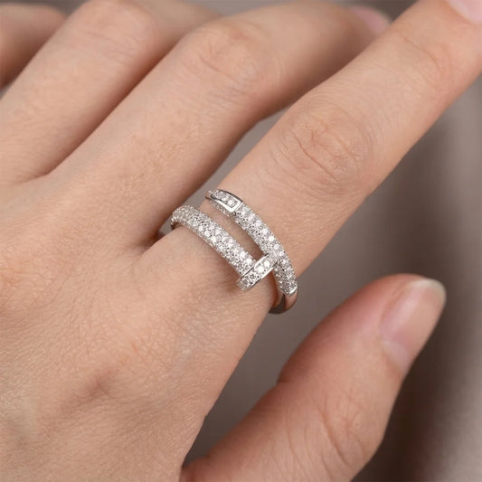 Silver ring with diamonds on a person's finger against a neutral background