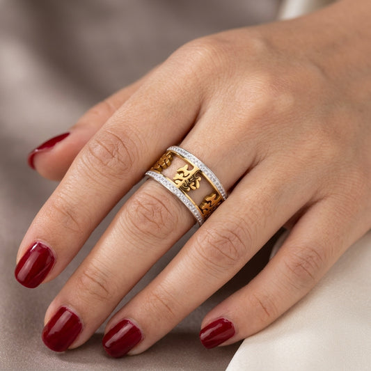 Close-up of a hand wearing two gold rings with red nail polish on a neutral background