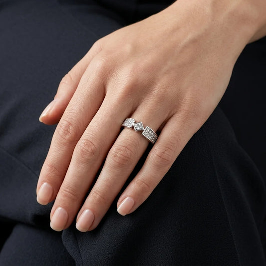 A close-up of a hand wearing a silver ring with three marquise-cut diamonds and pavé-set diamonds on a dark navy background.