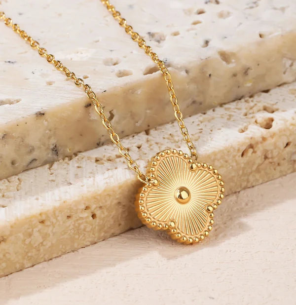 Gold necklace with a decorative pendant on a textured stone surface