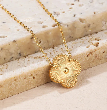 Gold necklace with a decorative pendant on a textured stone surface