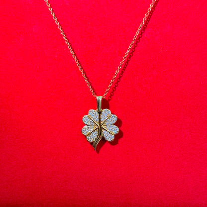 Gold necklace with a four-leaf clover pendant on a red background