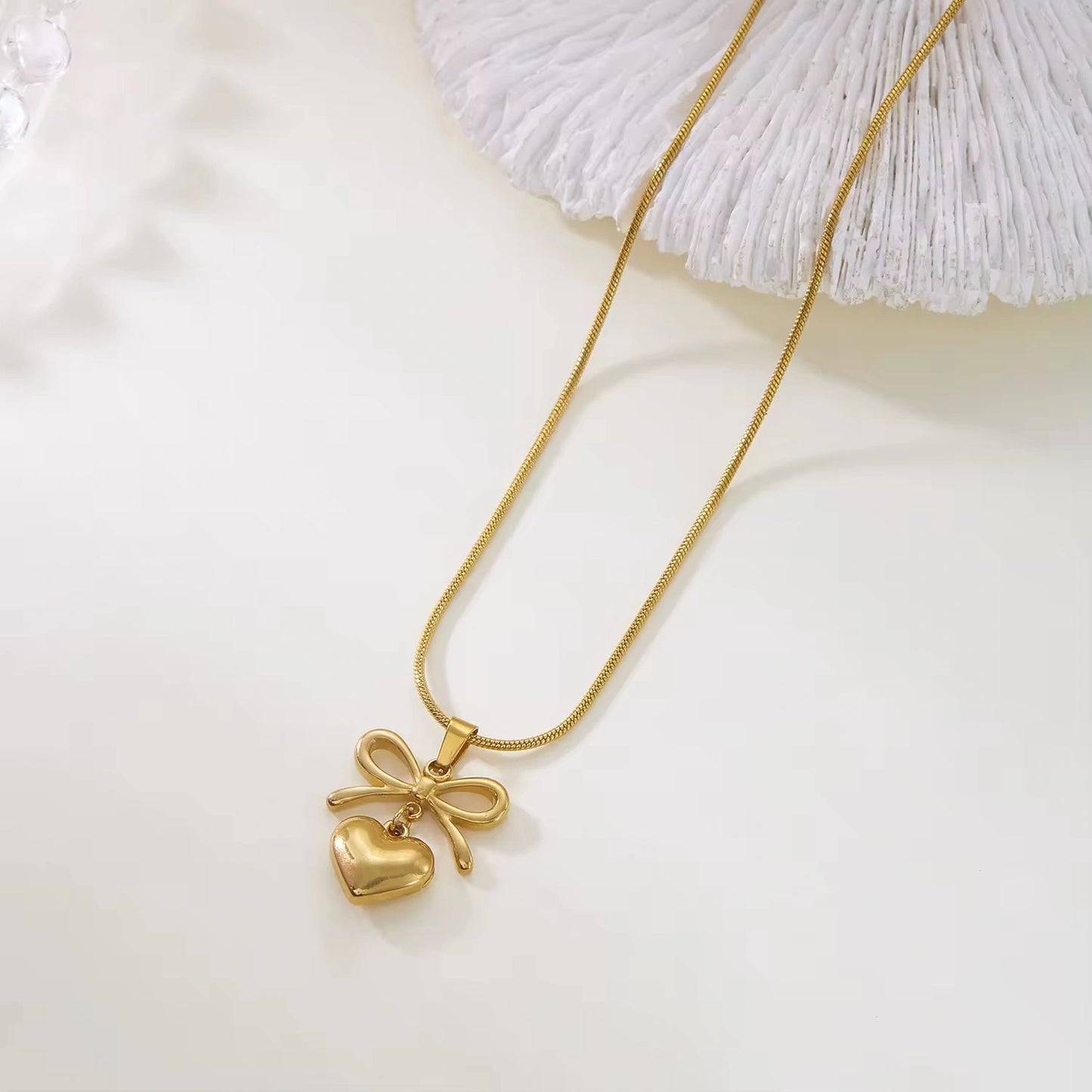 Gold necklace with a heart-shaped pendant on a light background