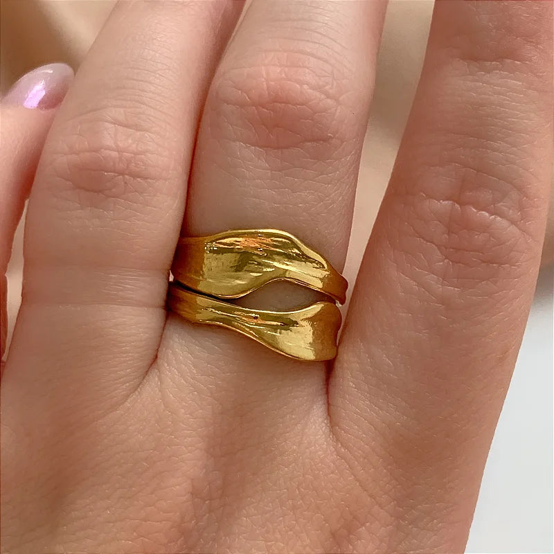 Gold ring on a person's finger with a plain background