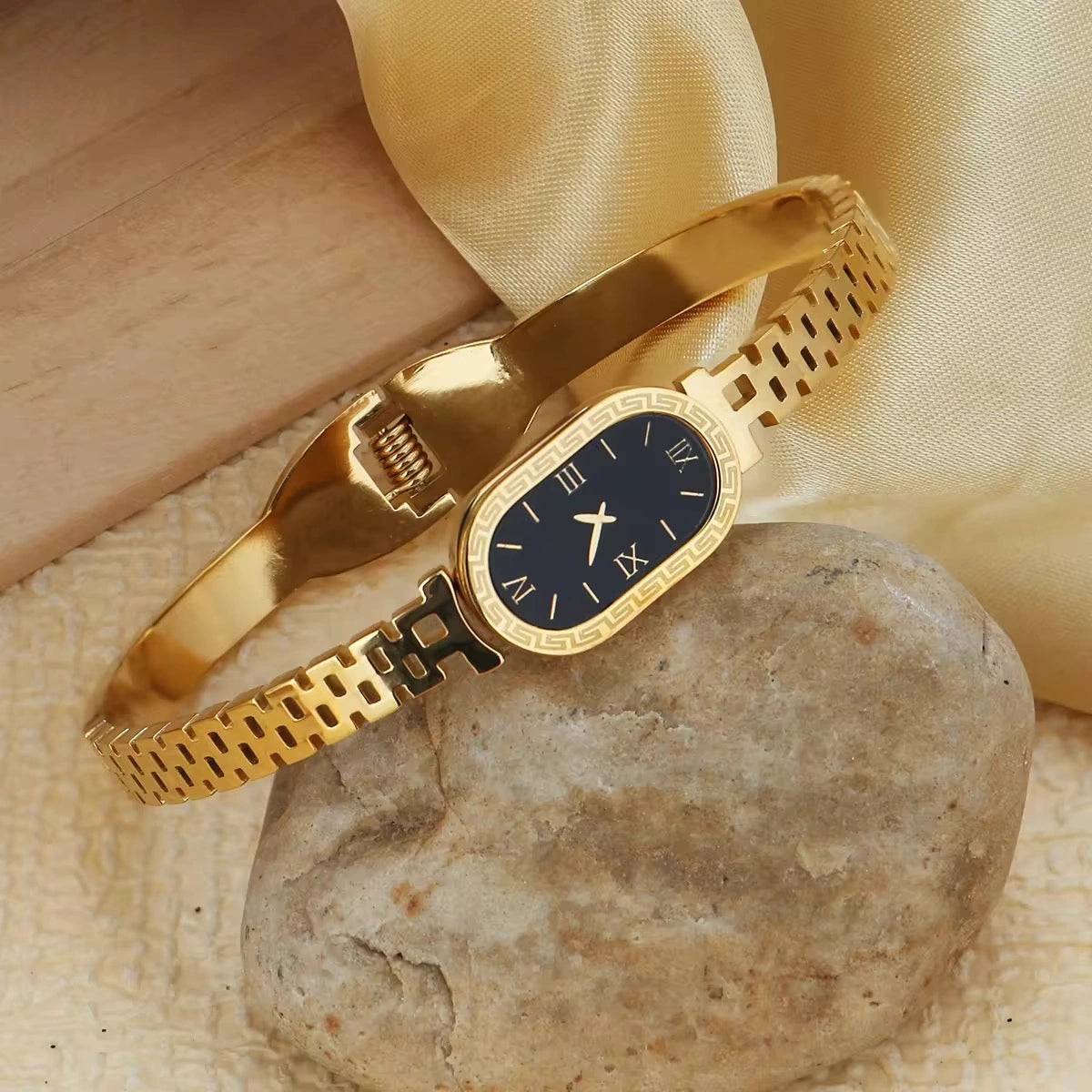 Gold bracelet with a black dial on a stone surface