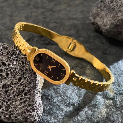 Gold bracelet with a black face on a textured stone surface