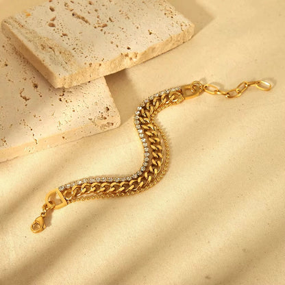 Gold chain bracelet with diamond accents on a beige stone surface