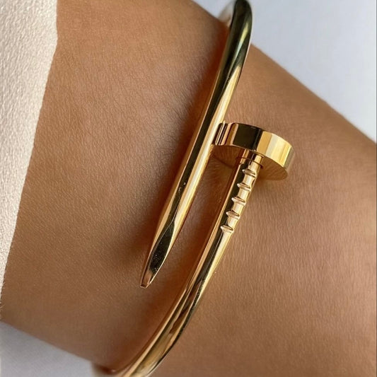 Gold bracelet on a wrist with a plain background