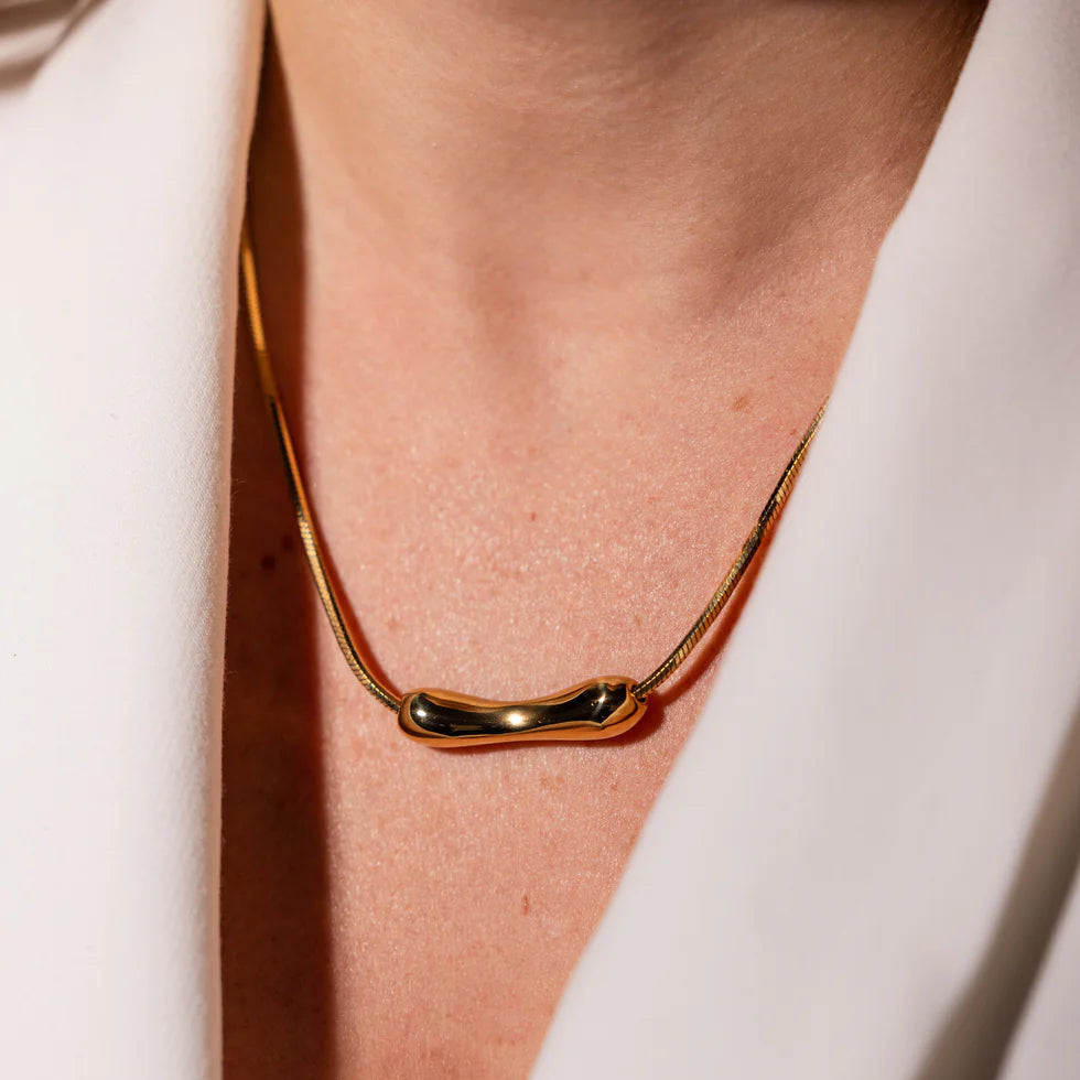 Gold necklace on a person wearing a white outfit