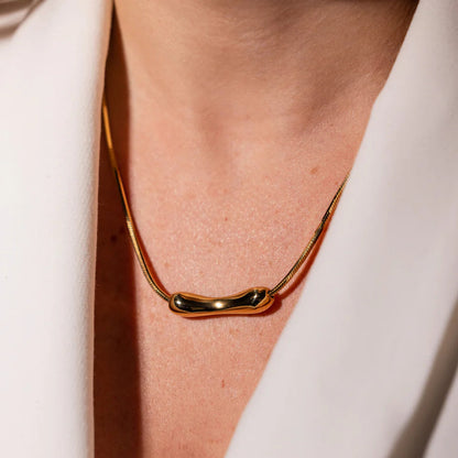 Gold necklace on a person wearing a white outfit