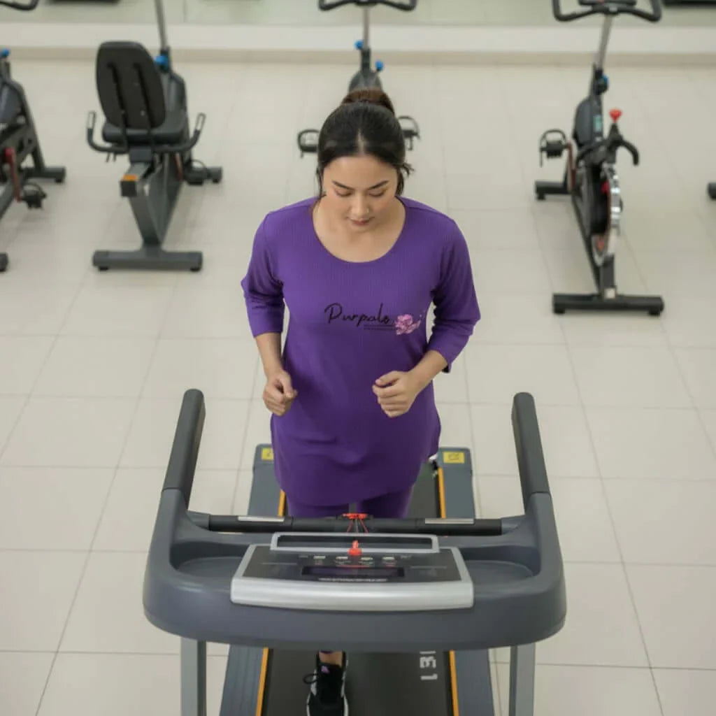 Woman in purple activewear running on treadmill in modern gym with exercise equipment
