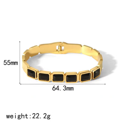 Gold bracelet with black stones and measurements on a white background