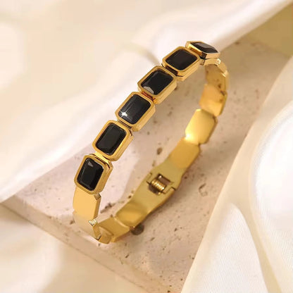 Gold bracelet with black stones on a light background