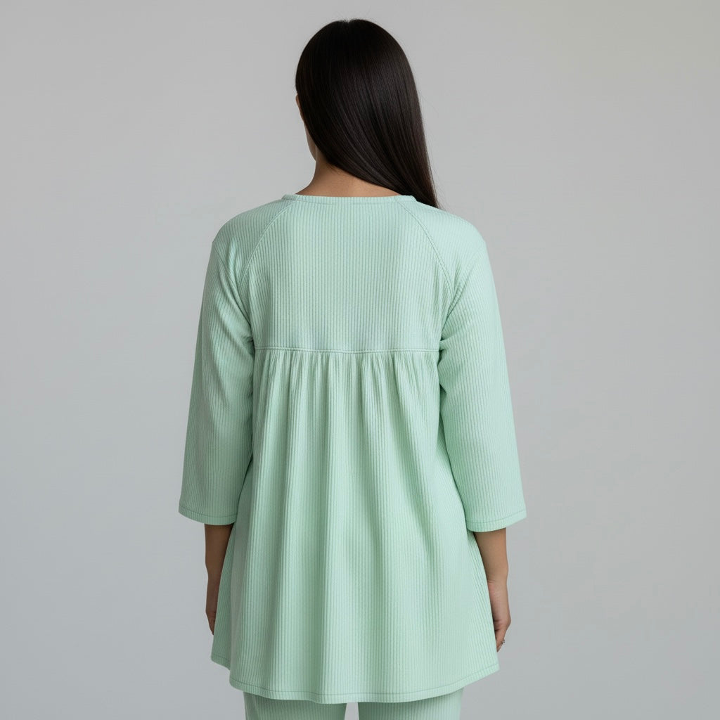 Person wearing a light green dress with a plain background