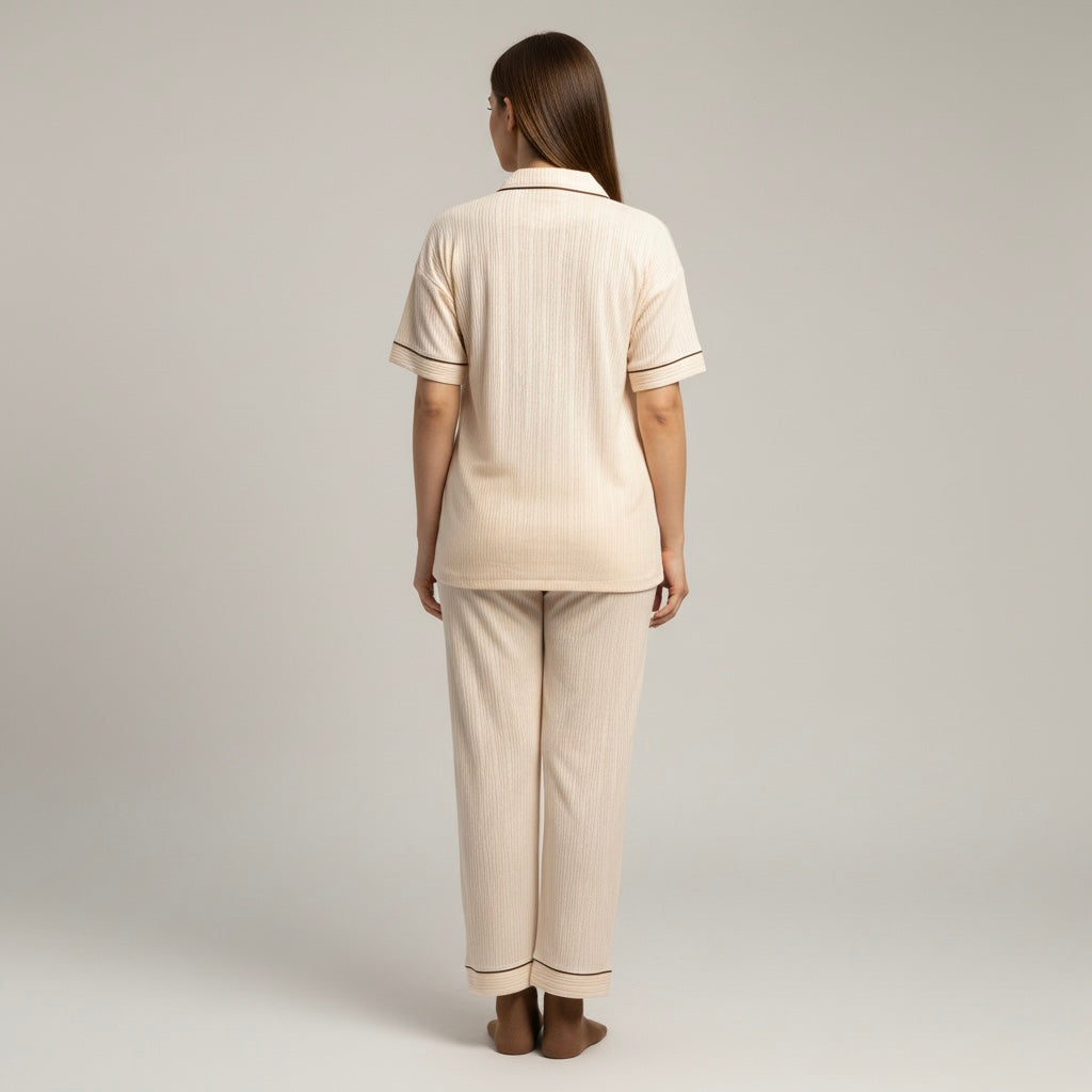 Woman wearing a beige pajama set against a plain background