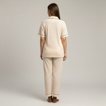 Woman wearing a beige pajama set against a plain background