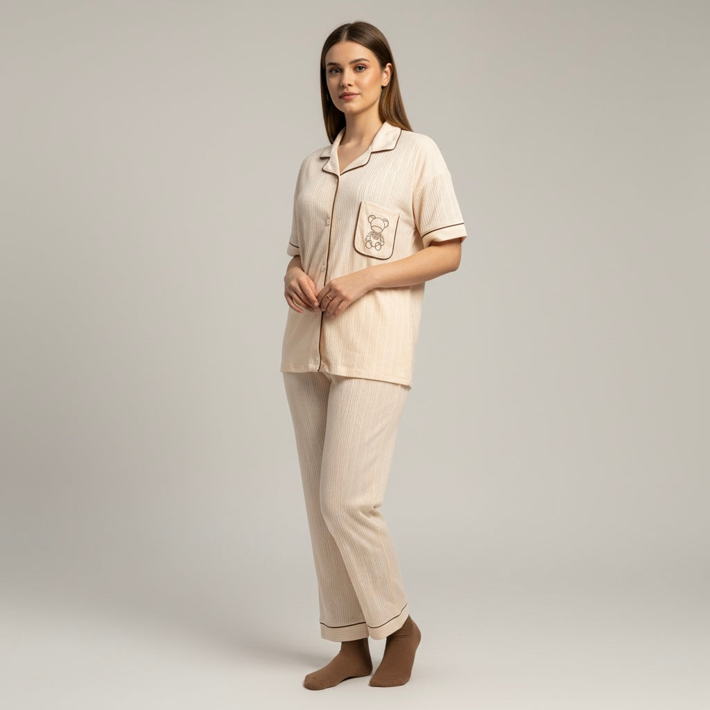 Woman wearing a beige pajama set with a teddy bear design on a plain background