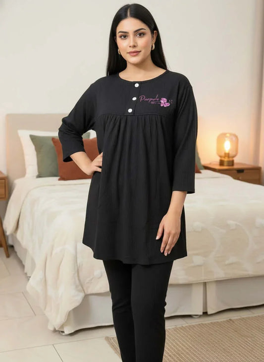 Woman in black nightwear set with Purpuls logo, standing in a modern bedroom