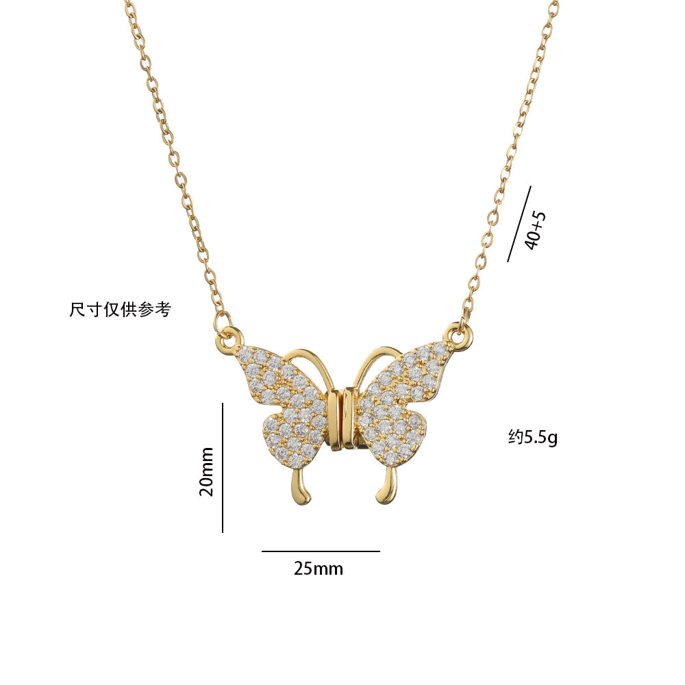 Gold butterfly necklace with diamond accents on a light pink fabric background
