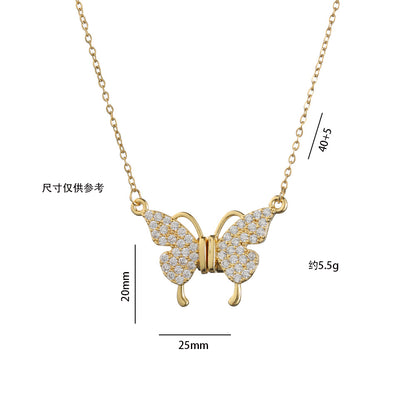 Gold butterfly necklace with diamond accents on a light pink fabric background