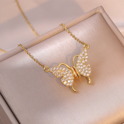 Gold butterfly necklace with diamond accents on a light pink fabric background