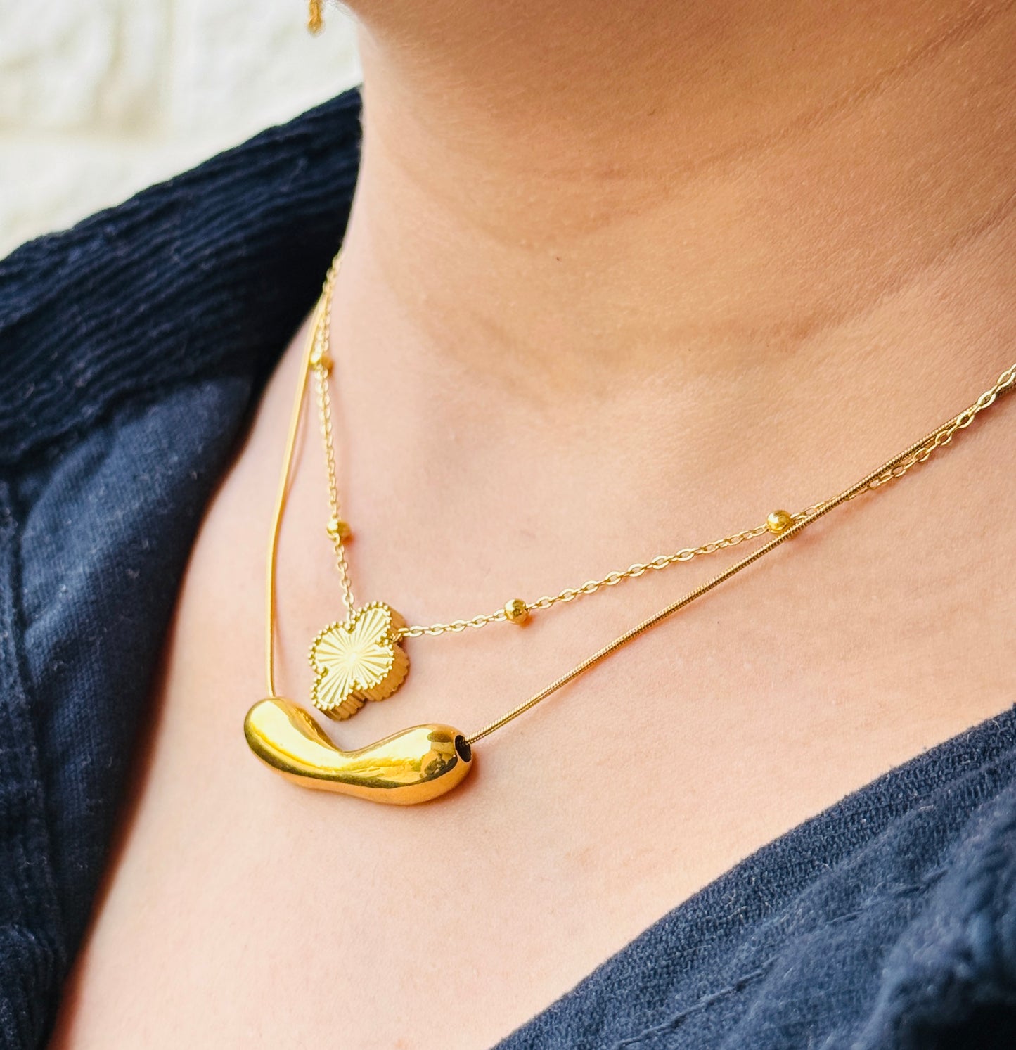 Close-up of a person wearing a gold necklace with a blue top.