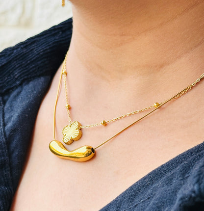 Close-up of a person wearing a gold necklace with a blue top.