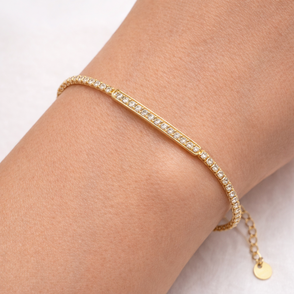 Gold bracelet with small diamonds on a wrist against a light background