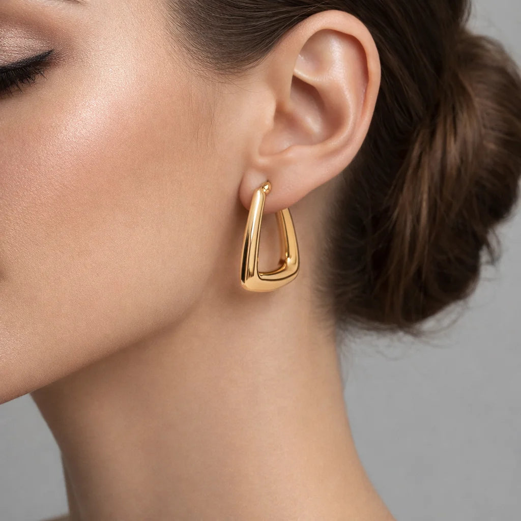 Gold hoop earring worn by a person with a neutral background