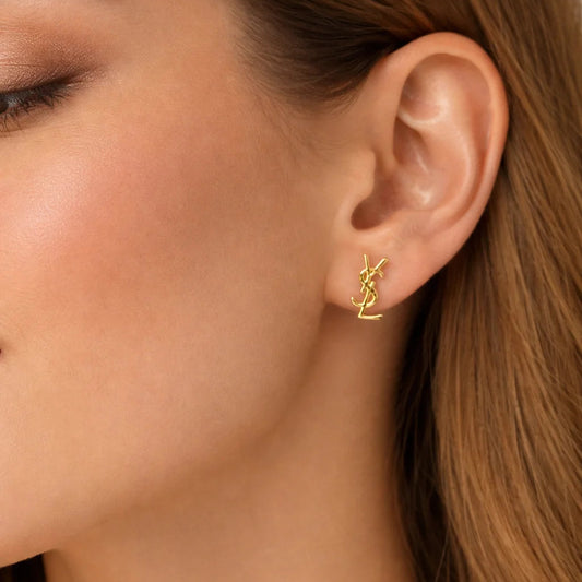 Close-up of a person wearing a gold earring with a visible brand logo.