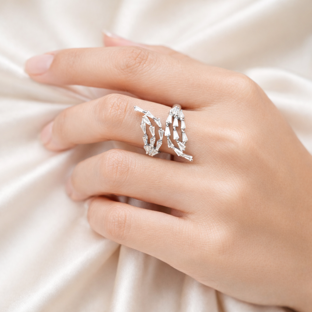Hand wearing a silver ring with a diamond on a light fabric background
