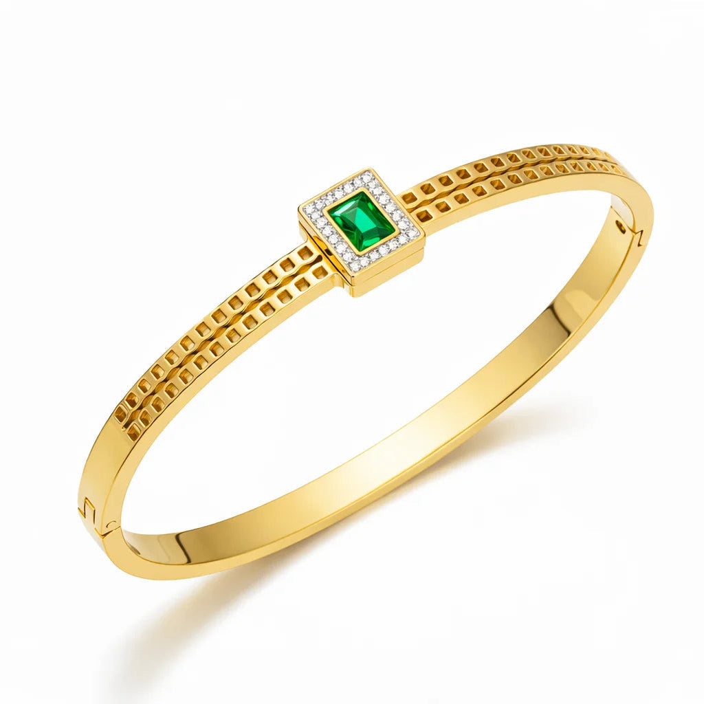 Gold bracelet with a green gemstone on a white background