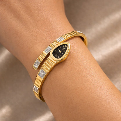 Gold bracelet with a snake design on a wrist against a neutral background