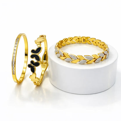Three gold bracelets on a white stand with a white background