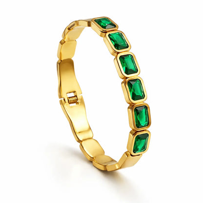 Gold bracelet with green gemstones on a white background